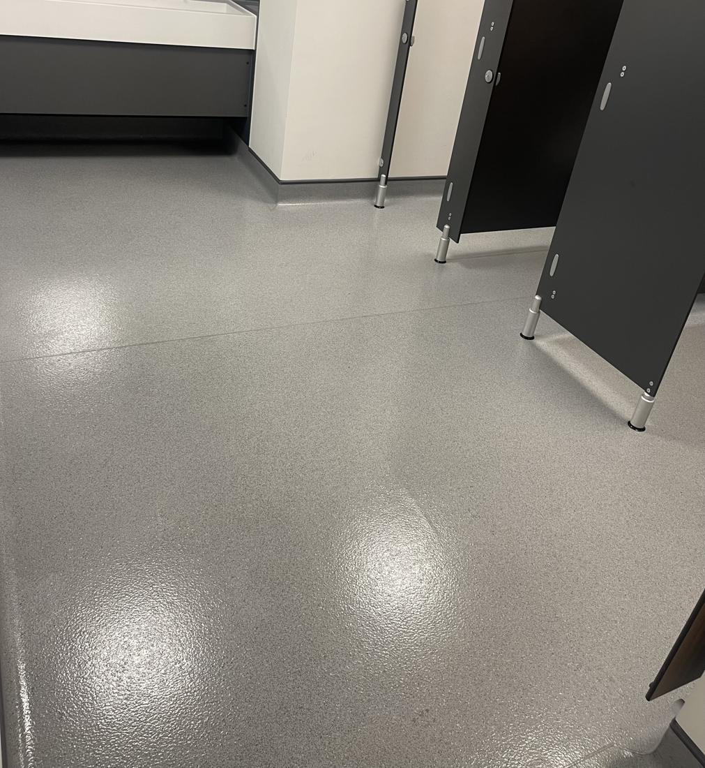 A clean accessible toilet with grab rails and hand basin at a workplace cleaned by Cadence Clean
