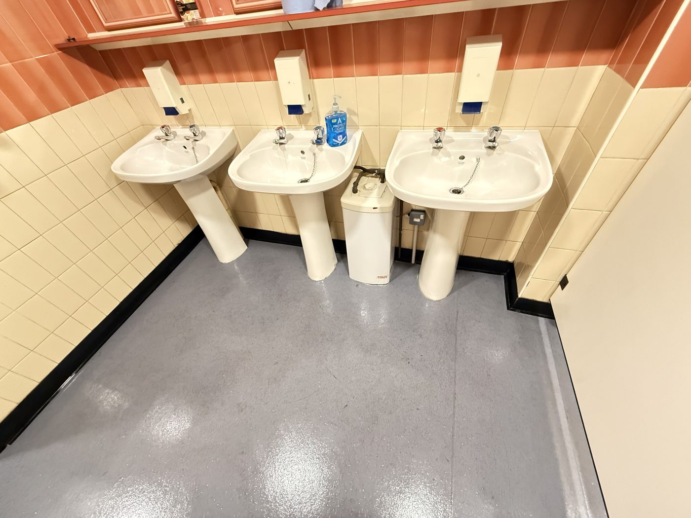 Three clean pedestal sinks in a shared washroom cleaned by Cadence Clean