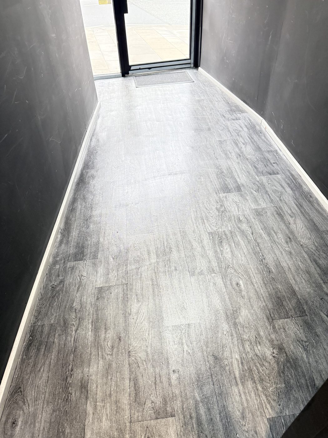 A clean entrance hallway with wood effect flooring at a shared building cleaned by Cadence Clean