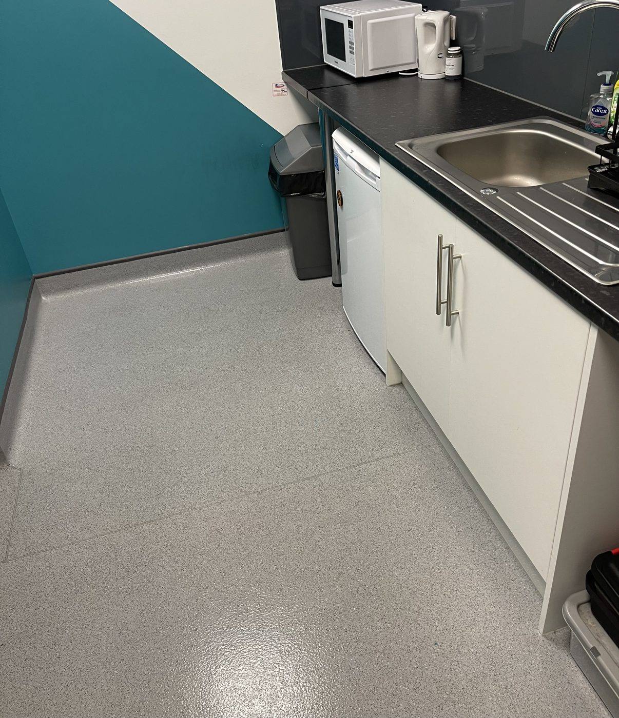 A clean staff kitchen with sink, microwave and safety flooring at a Derby office cleaned by Cadence Clean