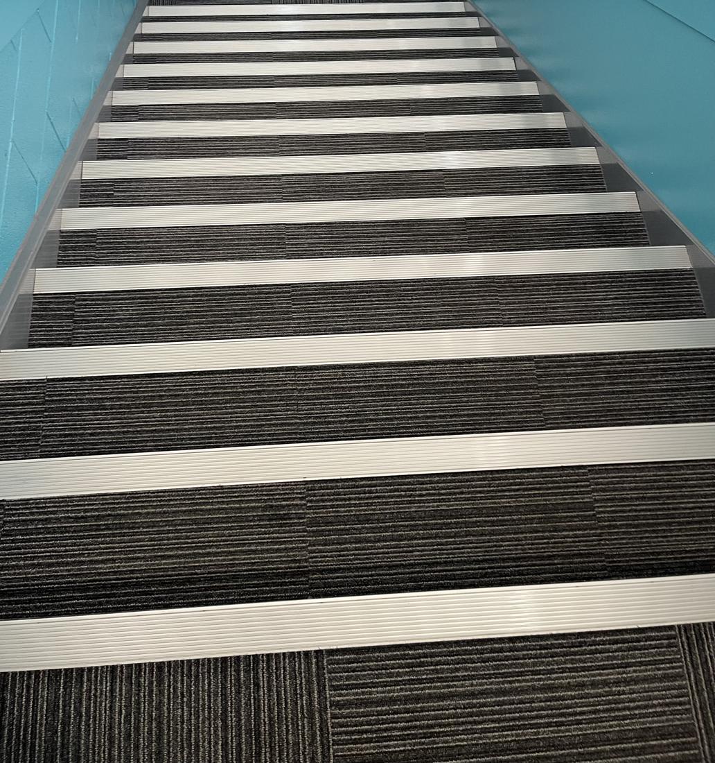 A clean communal staircase with carpet tile treads and aluminium nosings cleaned by Cadence Clean in Derby